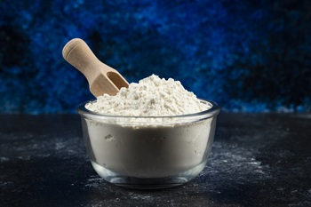 Glass bowl of flour on blue background Glass bowl of flour on blue background